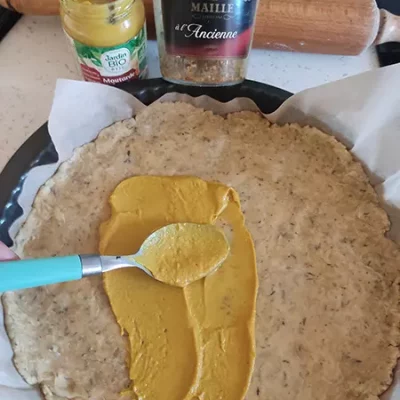 Étaler un couche de moutarde sur la pâte brisée