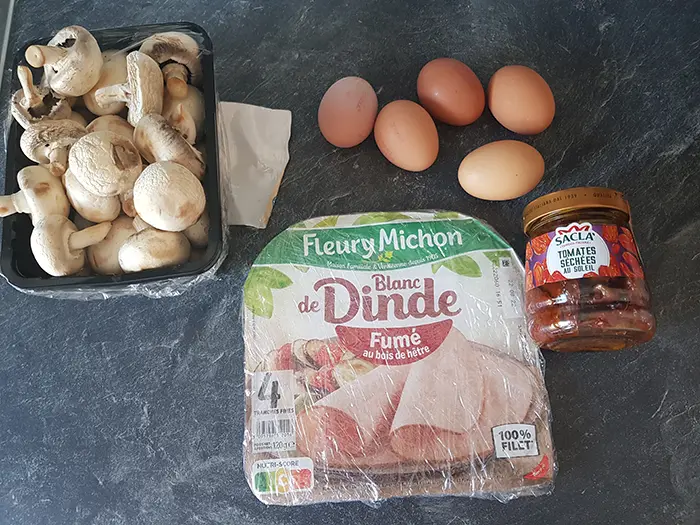 Ingrédients pour une omelette soufflée avec des champignons, du jambon cru et tomates séchées