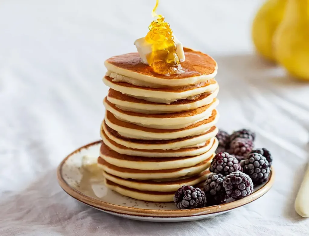 Pancakes nappés de miel, garnis de mûres.