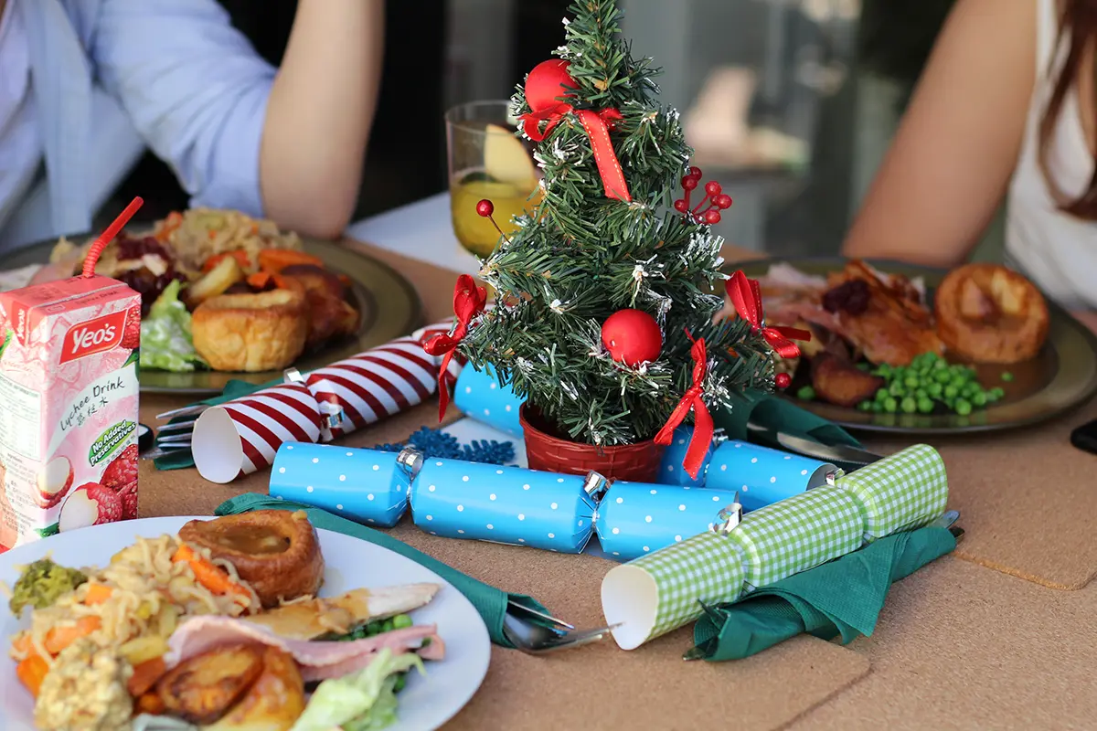 Famille réunie autour d’une table décorée, avec un mini sapin de Noël au centre et des plats festifs
