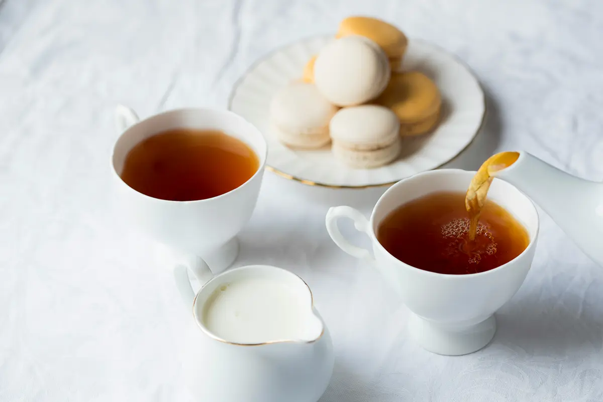 Deux verres de thé à la menthe fumant, servis avec une assiette de macarons colorés