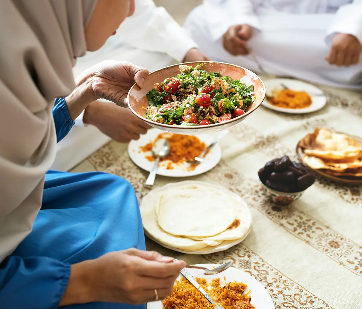Femme servant à sa famille un repas d’iftar traditionnel du ramadan avec plats variés et ambiance chaleureuse