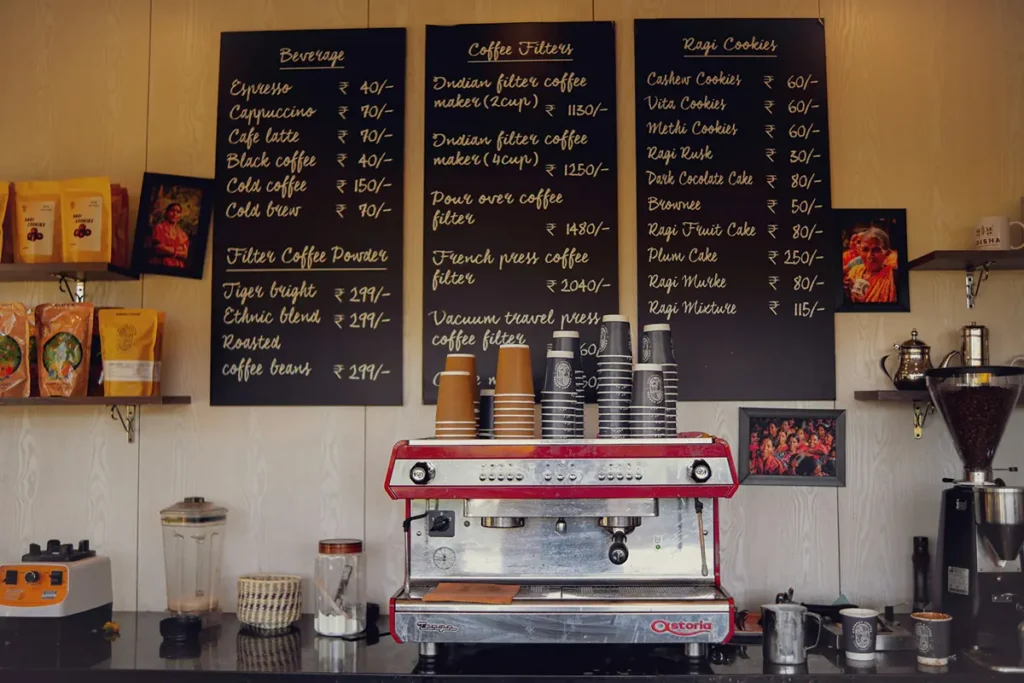 Machine à expresso sous des ardoises affichant les boissons et leurs prix en roupies.